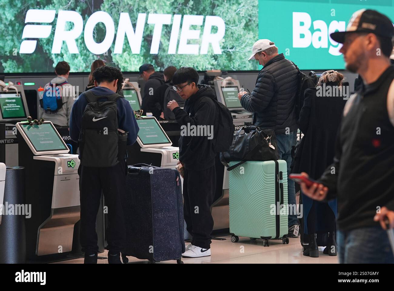 Travellers queue up at the Frontier Airlines self-check kiosks in ...