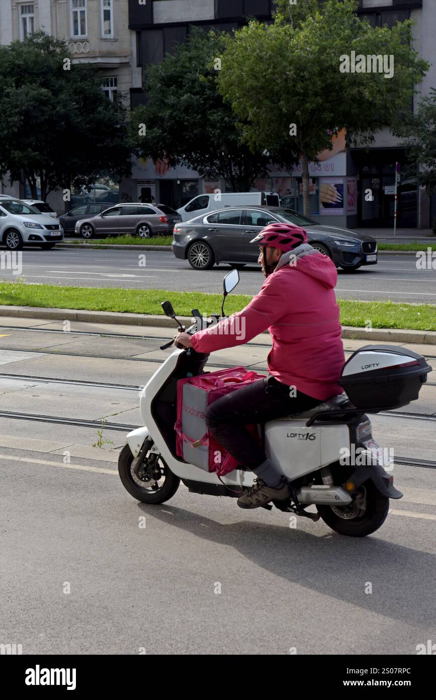 A moped rider delivering food for Foodora delivery in Vienna, Austria, June 2024 Stock Photo