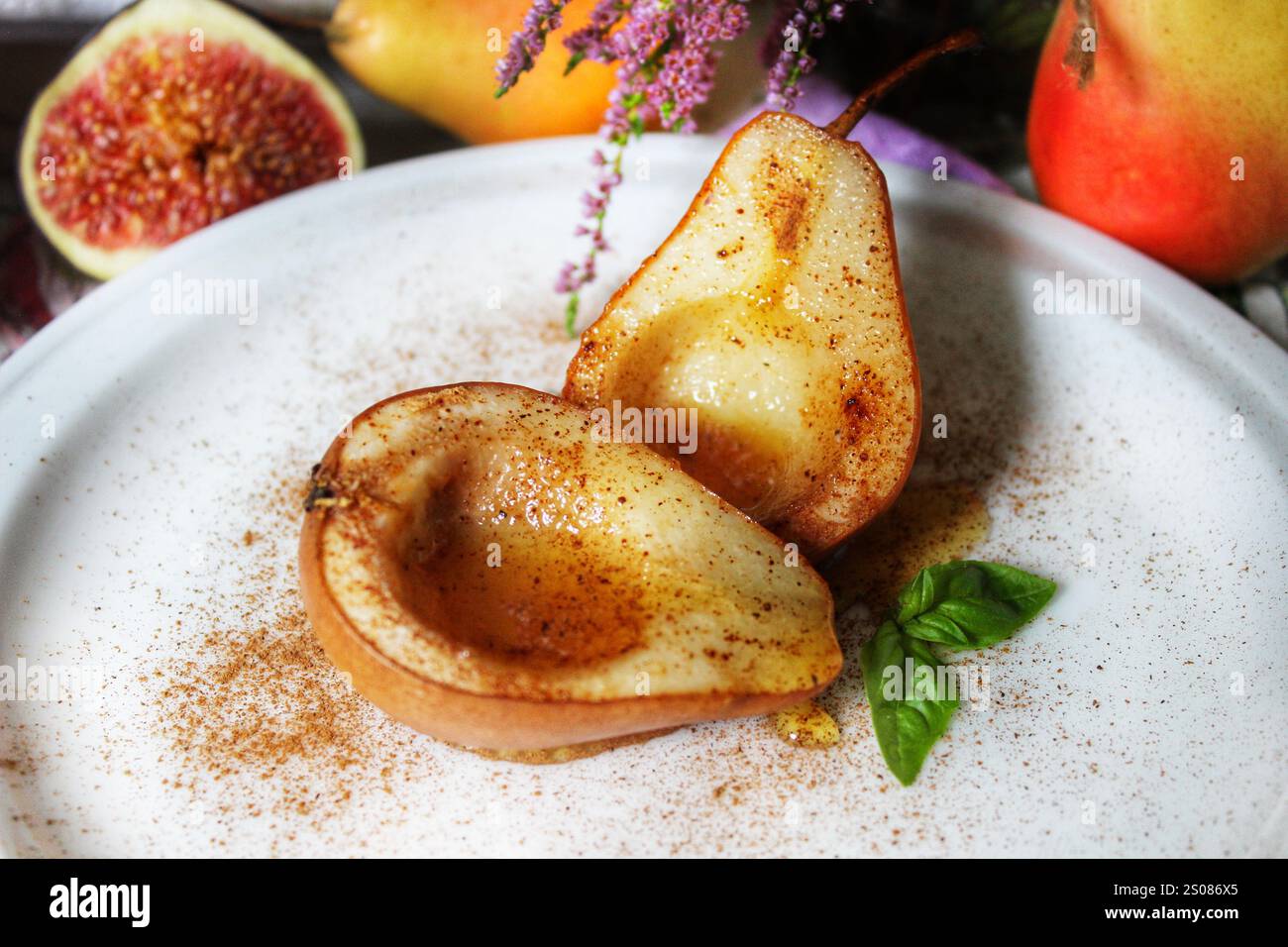 Baked pears with cinnamon and honey resting on white plate Stock Photo