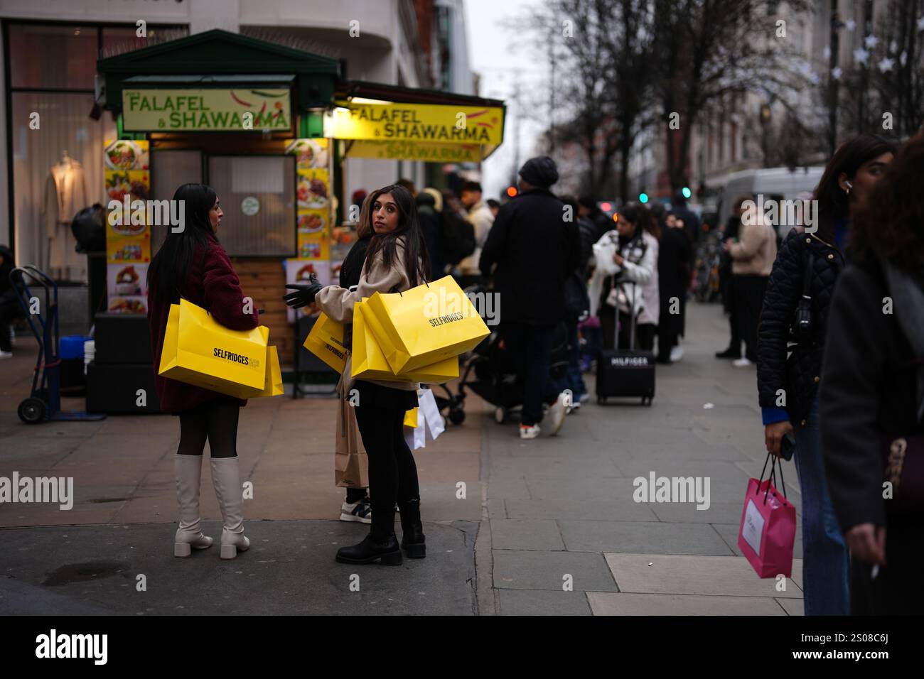Shoppers on Oxford Street, London, carrying bags from Selfridges during