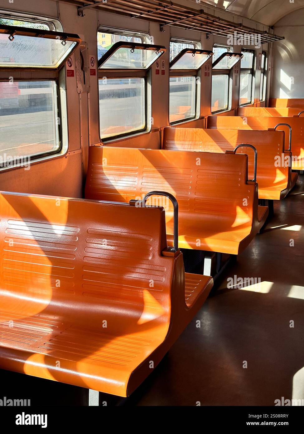 Vintage electric train car with orange seats, interior design. Retro transportation style, road trip Stock Photo
