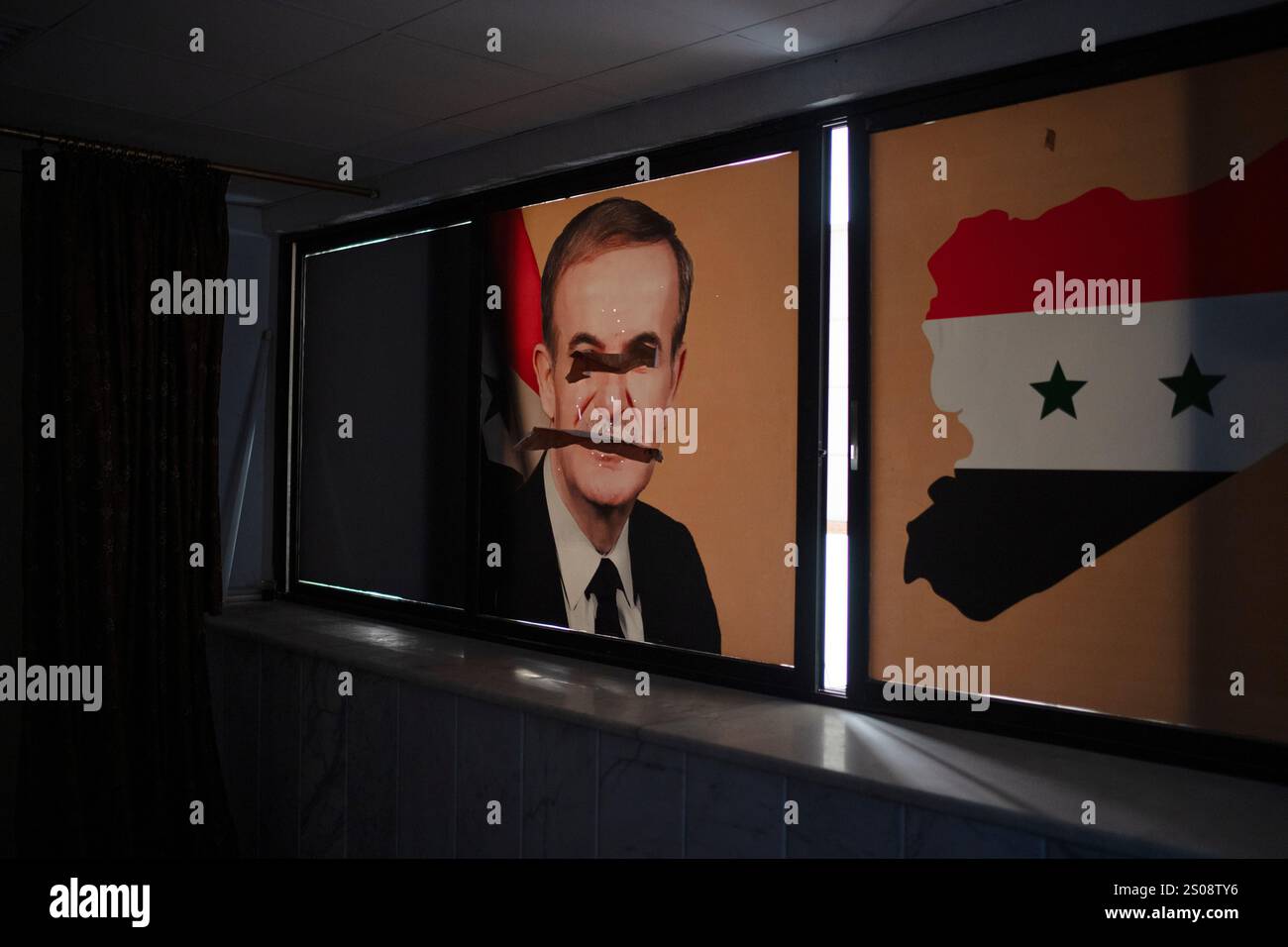 A damaged image depicting the late Syrian President Hafez al-Assad, is ...