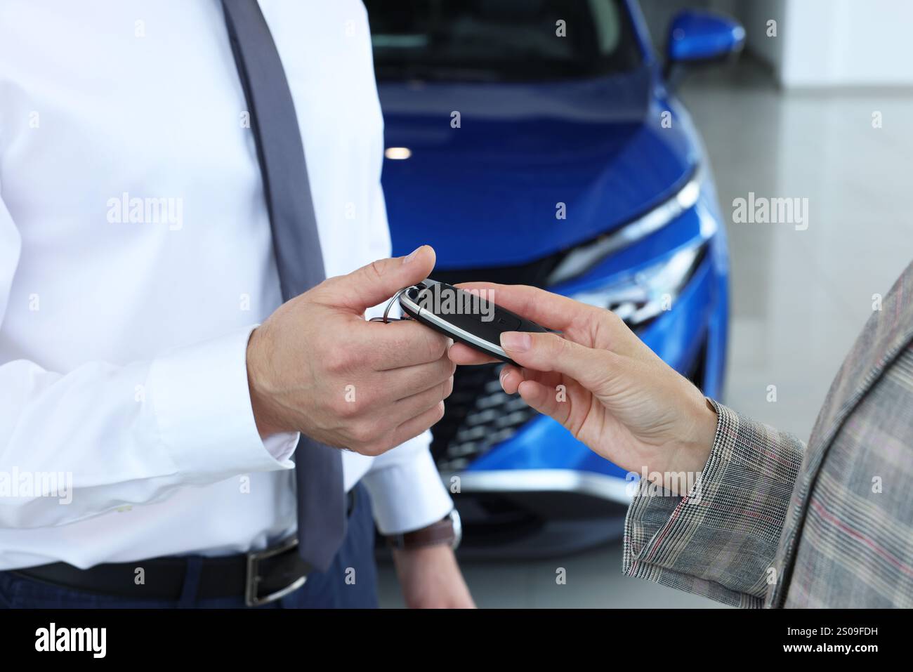 Saleswoman giving key to client near new car in salon, closeup Stock ...