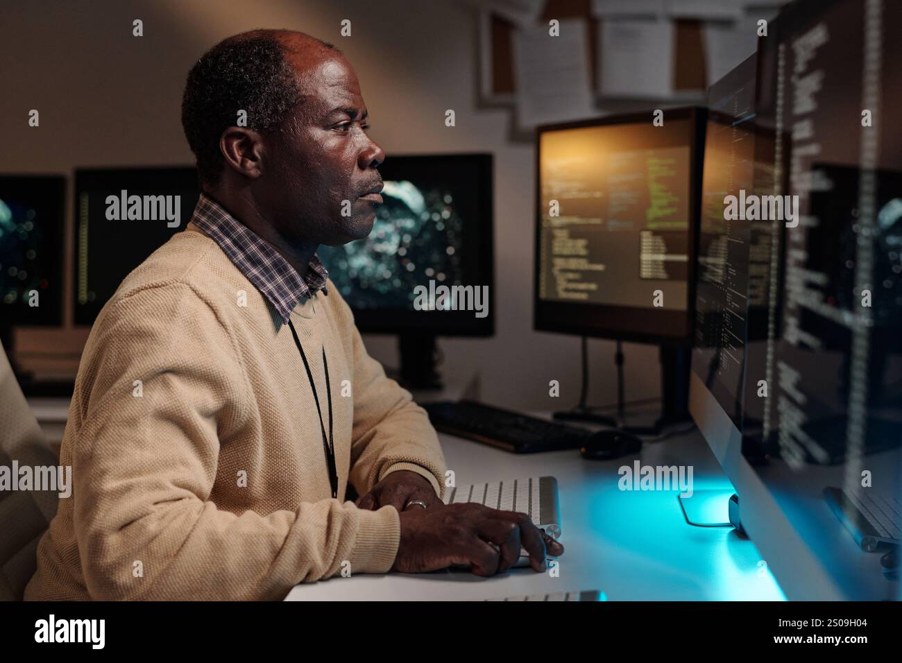 Serious male IT engineer keeping hand on computer mouse and looking at screen while developing new software in office Stock Photo