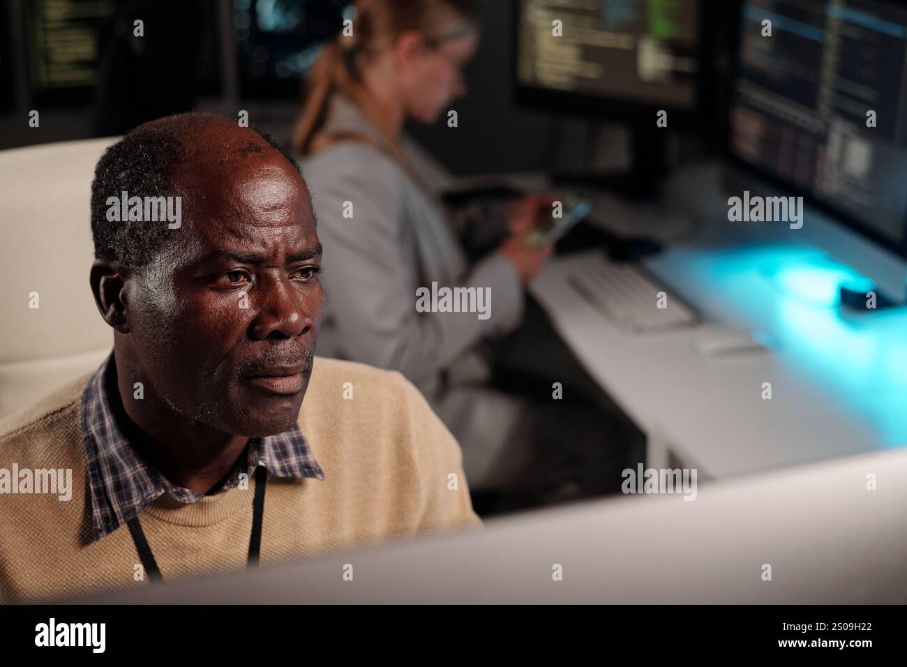 Serious experienced IT engineer looking at desktop computer screen while decoding online data or developing new software Stock Photo