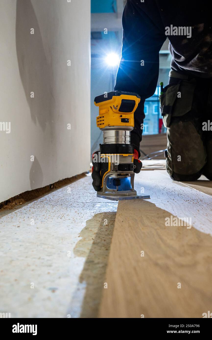 An individual operates a yellow and black router on a wooden floor ...