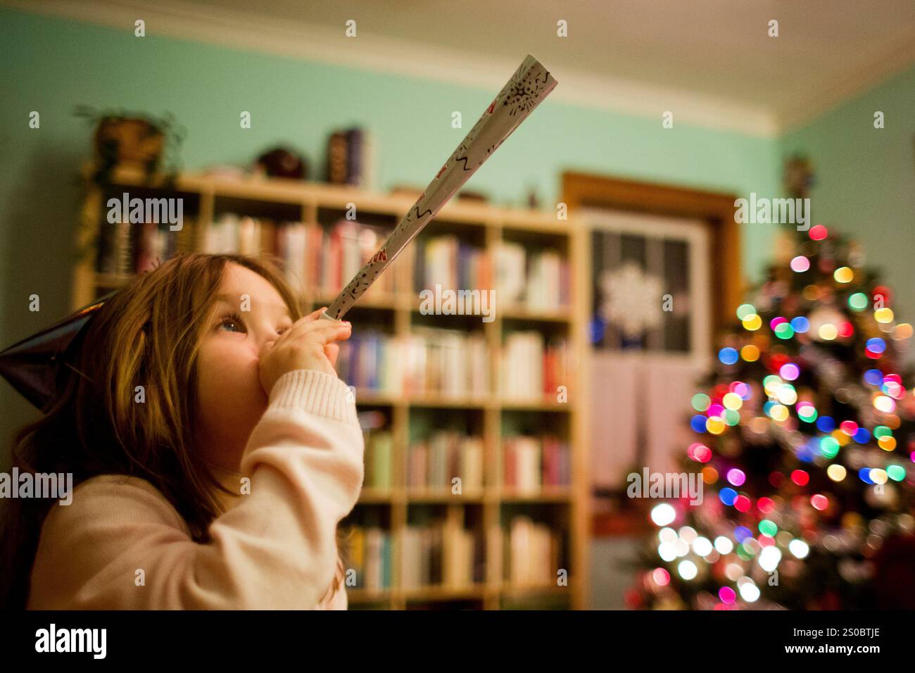 Girl blowing party horn during Christmas Stock Photo - Alamy