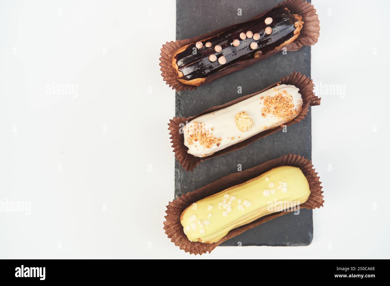 Three eclairs on a black tray top view Stock Photo