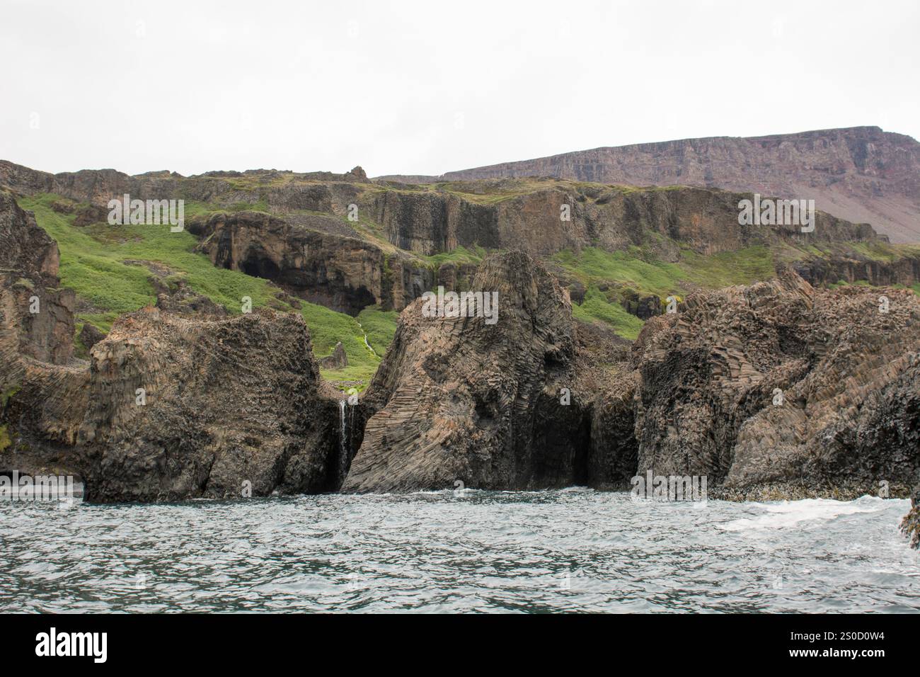 A striking natural formation of basalt columns on Disko Island, Greenland, showcasing the island's unique geological beauty. These towering hexagonal Stock Photo