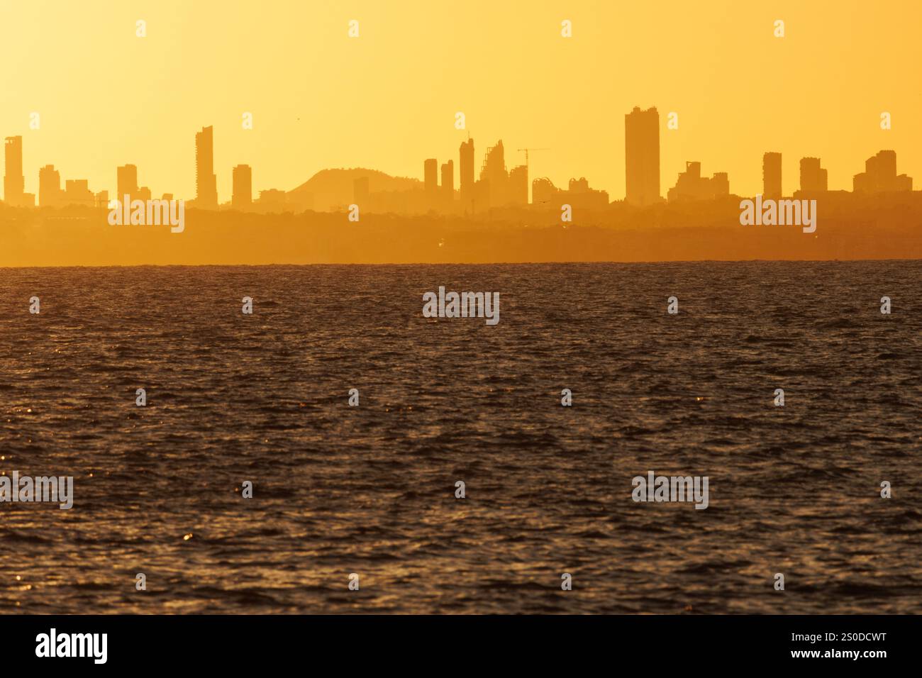 Sunset with the urban skyline of Benidorm city from the seafront of the Peon de Ifach in Calpe, Spain Stock Photo