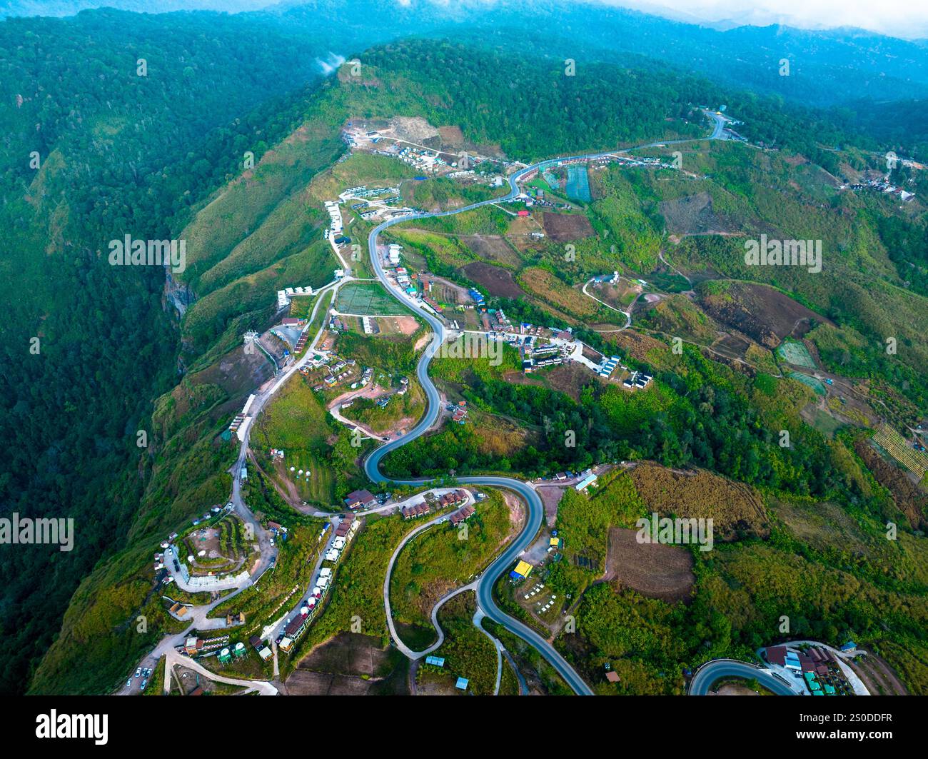 aerial view of a winding mountain road surrounded by lush greenery ...
