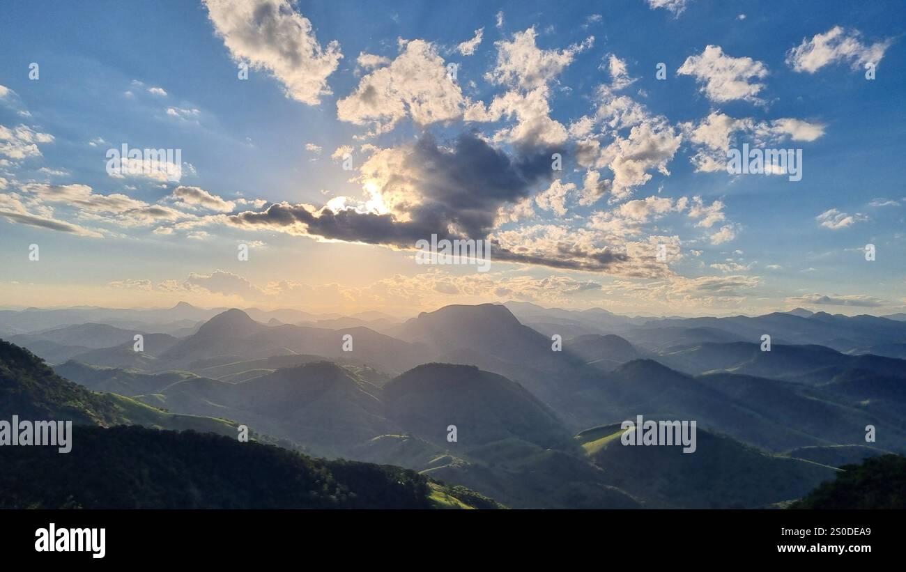 A breathtaking view of the sun setting over a serene landscape of rolling hills and distant mountain ranges. - Smartphone Captured Stock Image