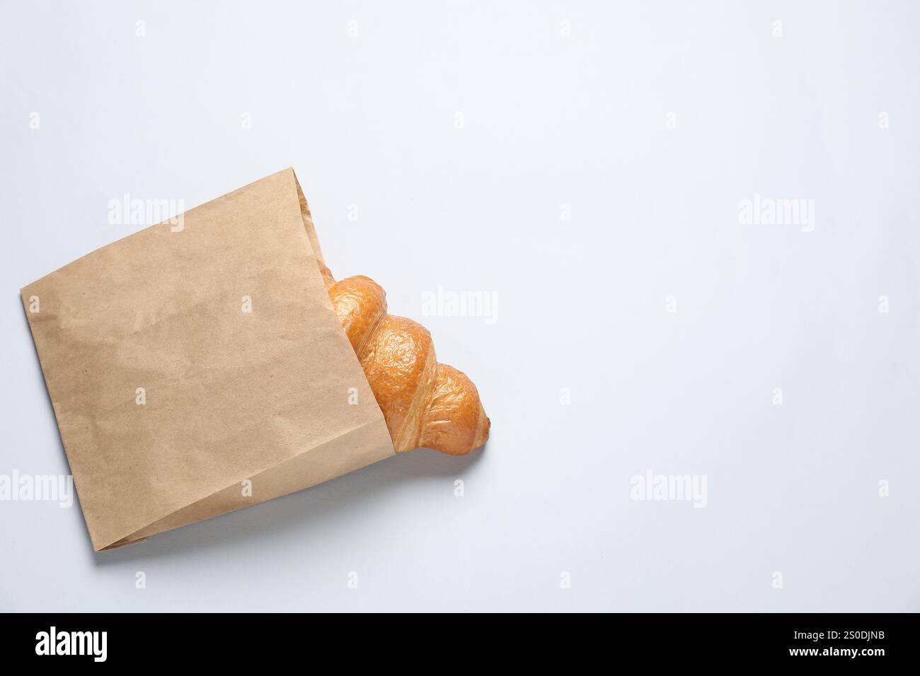Paper bag with fresh croissant on white background, top view. Space for ...