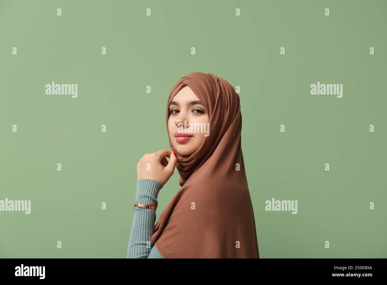 Beautiful young Muslim woman in hijab on green background Stock Photo ...