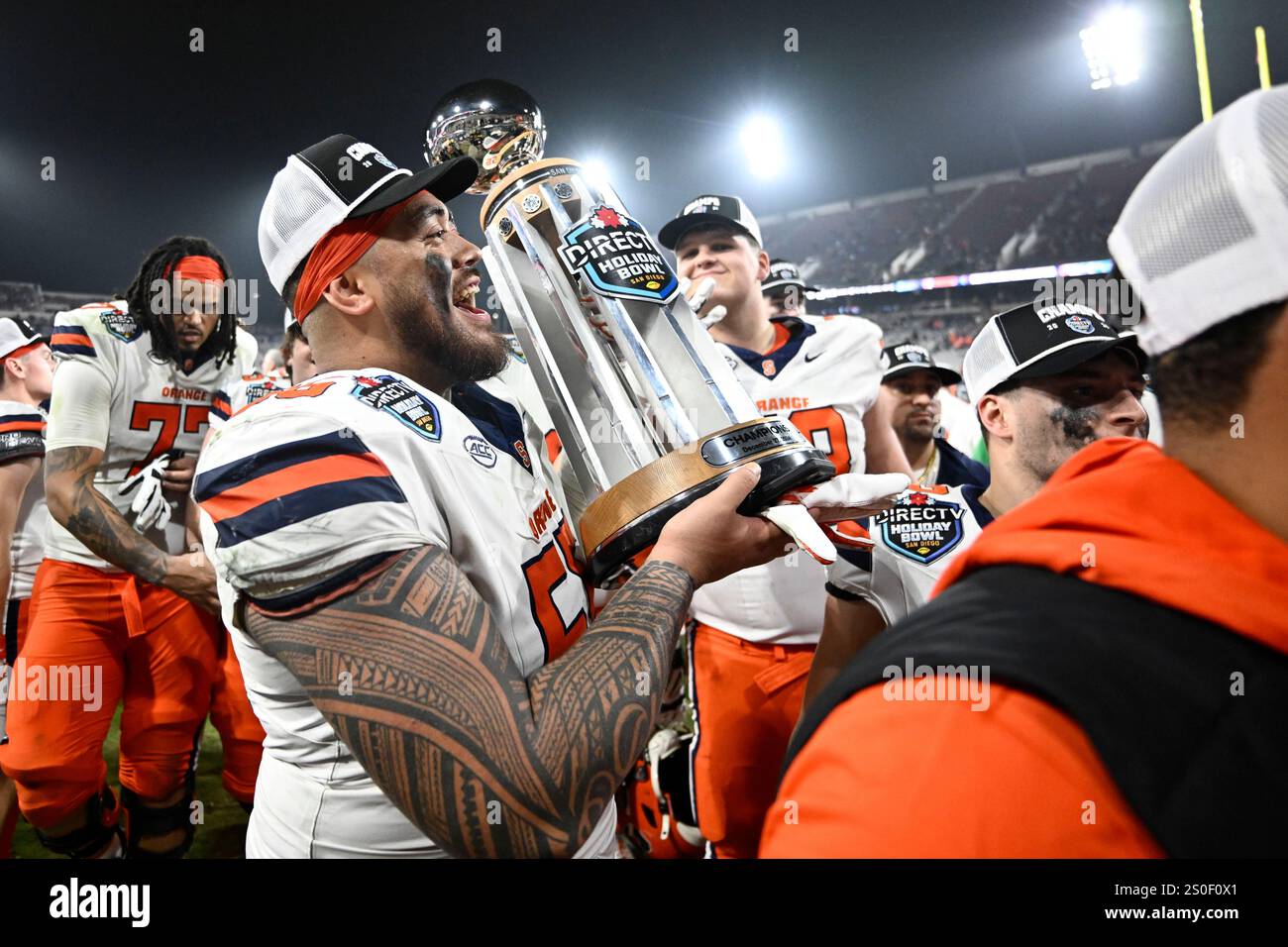 Syracuse offensive lineman Josh Ilaoa (55) holds up the Holiday Bowl