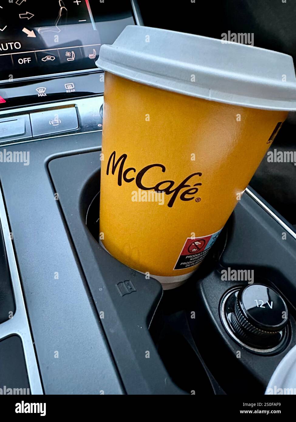 A coffee by McCafe in a paper cup for takeaway in the holder of a car - Smartphone Captured Stock Image