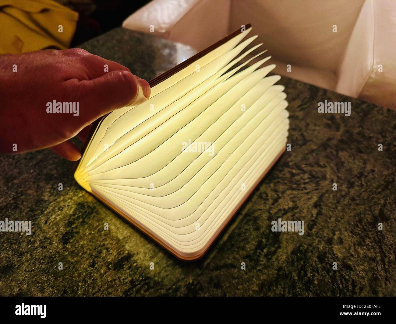 A book lamp on a table, pages are illuminated by an LED light within - Smartphone Captured Stock Image
