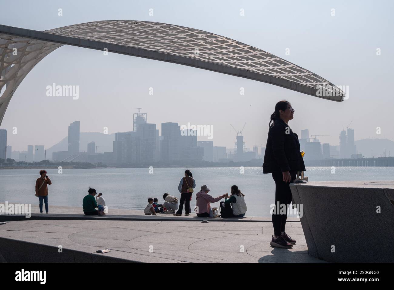 Shenzhen, China. 28th Dec, 2024. Tourists seen enjoy a view of the Qianhai bay at the Bao'an Haibin Culture Park in Shenzhen, China. (Photo by Peerapon Boonyakiat/SOPA Images/Sipa USA) Credit: Sipa USA/Alamy Live News Stock Photo