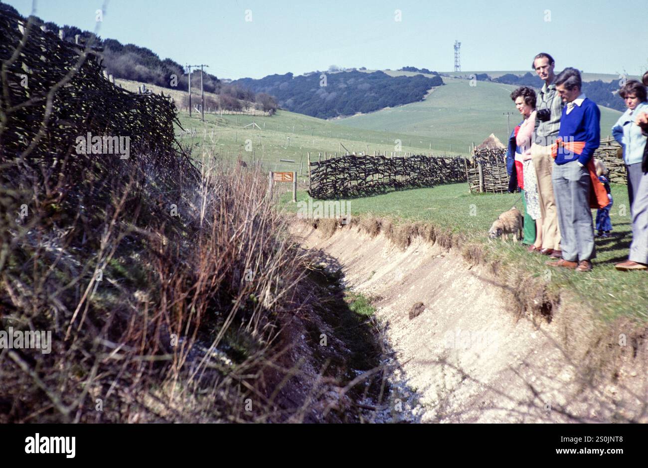 People looking at ditch of Iron Age dwelling, Butser Ancient Farm experimental archaeology site  Petersfield, Hampshire, England, UK 1980 Stock Photo