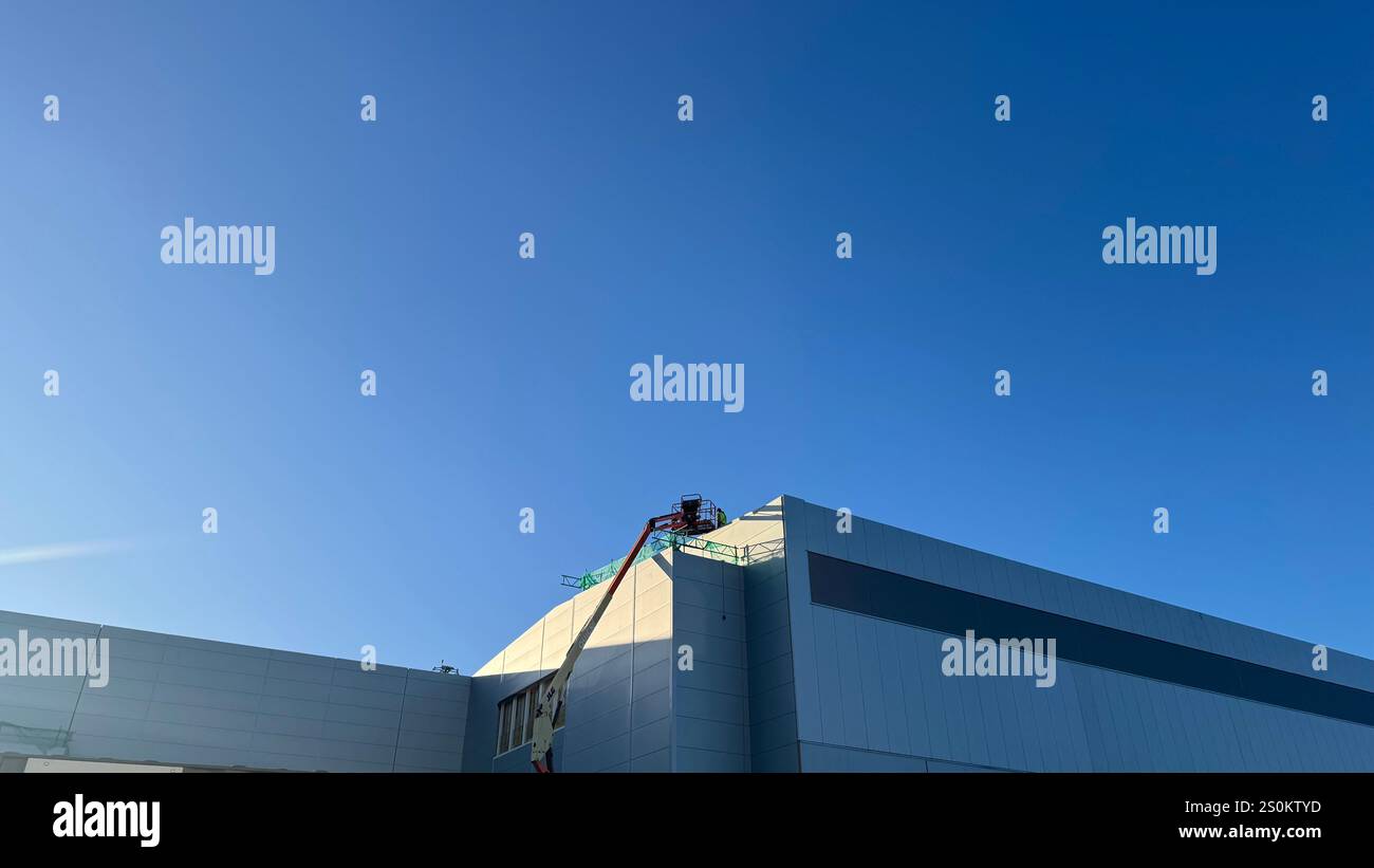 A mostly clear blue sky above a large, light gray building under ...