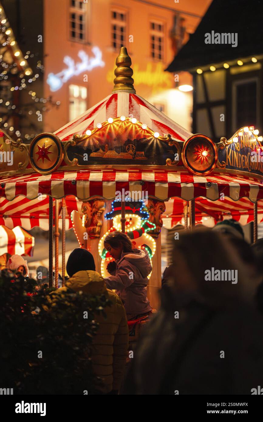 Lively Christmas market with a colourfully illuminated carousel in a ...