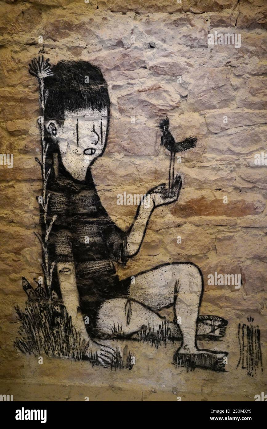 MAUSA VAUBAN, Museum of Urban Art and Street Art, Neuf-Brisach Fortress, France, Europe, Graffiti of a child holding a bird, surrounded by plants, on Stock Photo