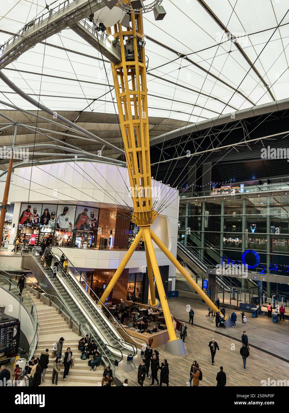 Interior view of the O2 arena a bustling modern shopping mall with a unique architectural design and people walking around the escalators and shops - Smartphone Captured Stock Image