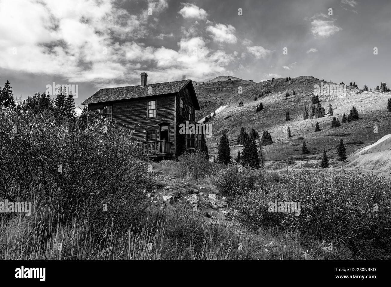 Wooden Cabin Amid Rugged Mountainous Landscape in Black and White Stock Photo