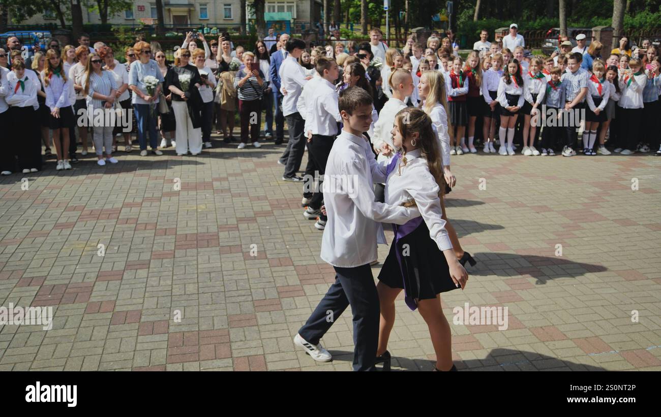 Berezovka, Belarus - May 31, 2024:Teenage students waltzing at their final school day event in the schoolyard, while teachers and parents observe and Stock Photo