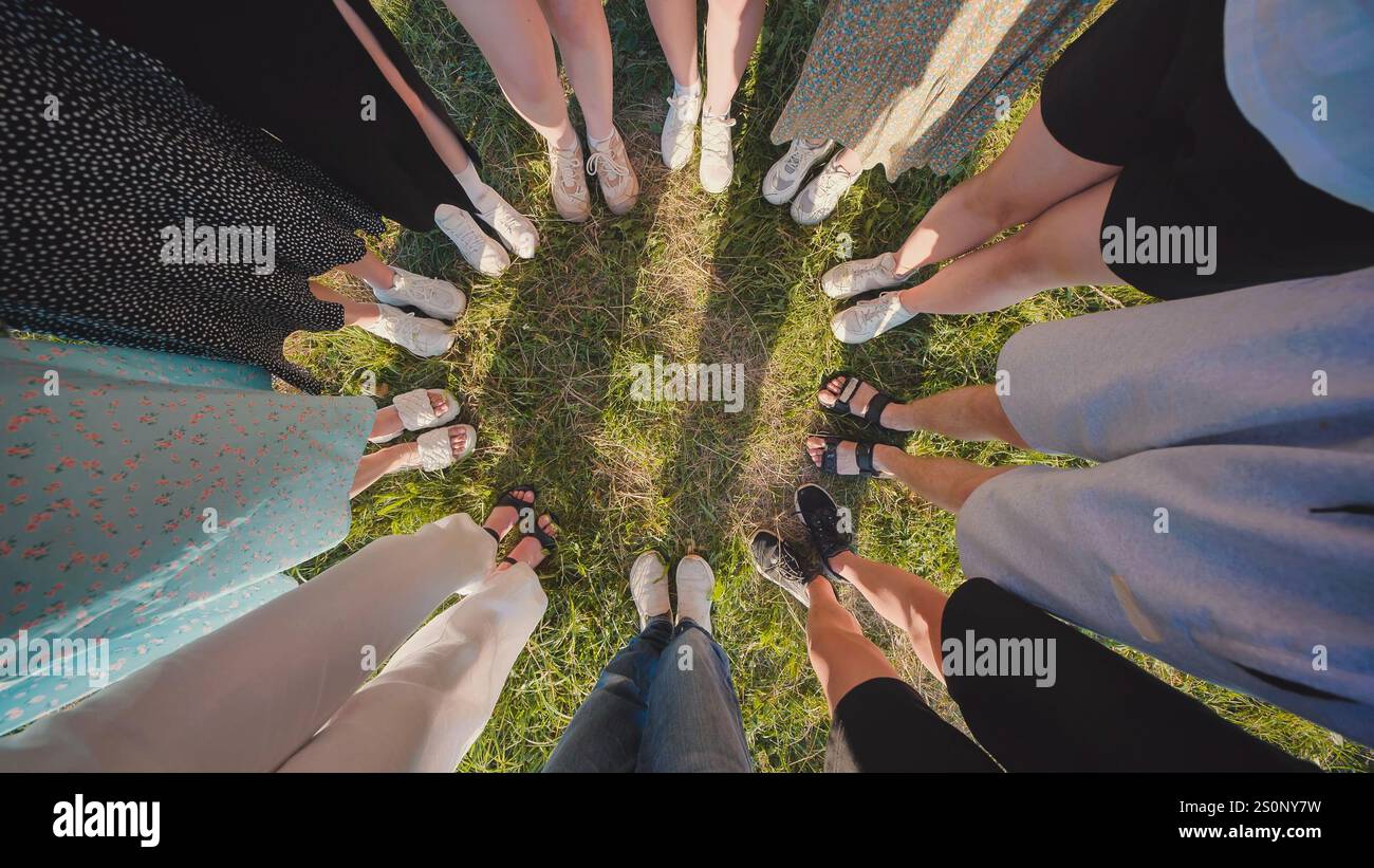 Diverse group of friends standing in a circle on lush green grass ...
