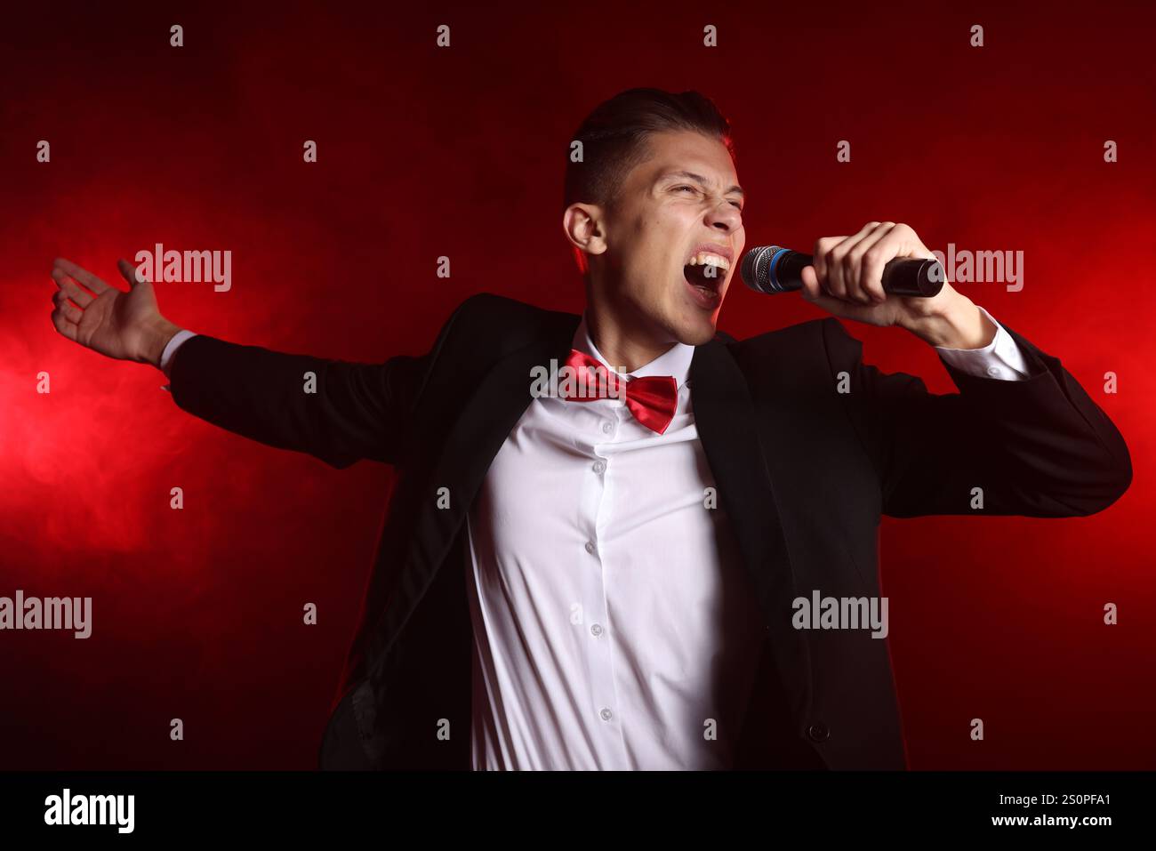 Talented singer performing on red background with smoke Stock Photo - Alamy