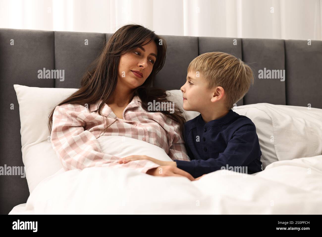 Overwhelmed mother with her son in bed at home Stock Photo - Alamy