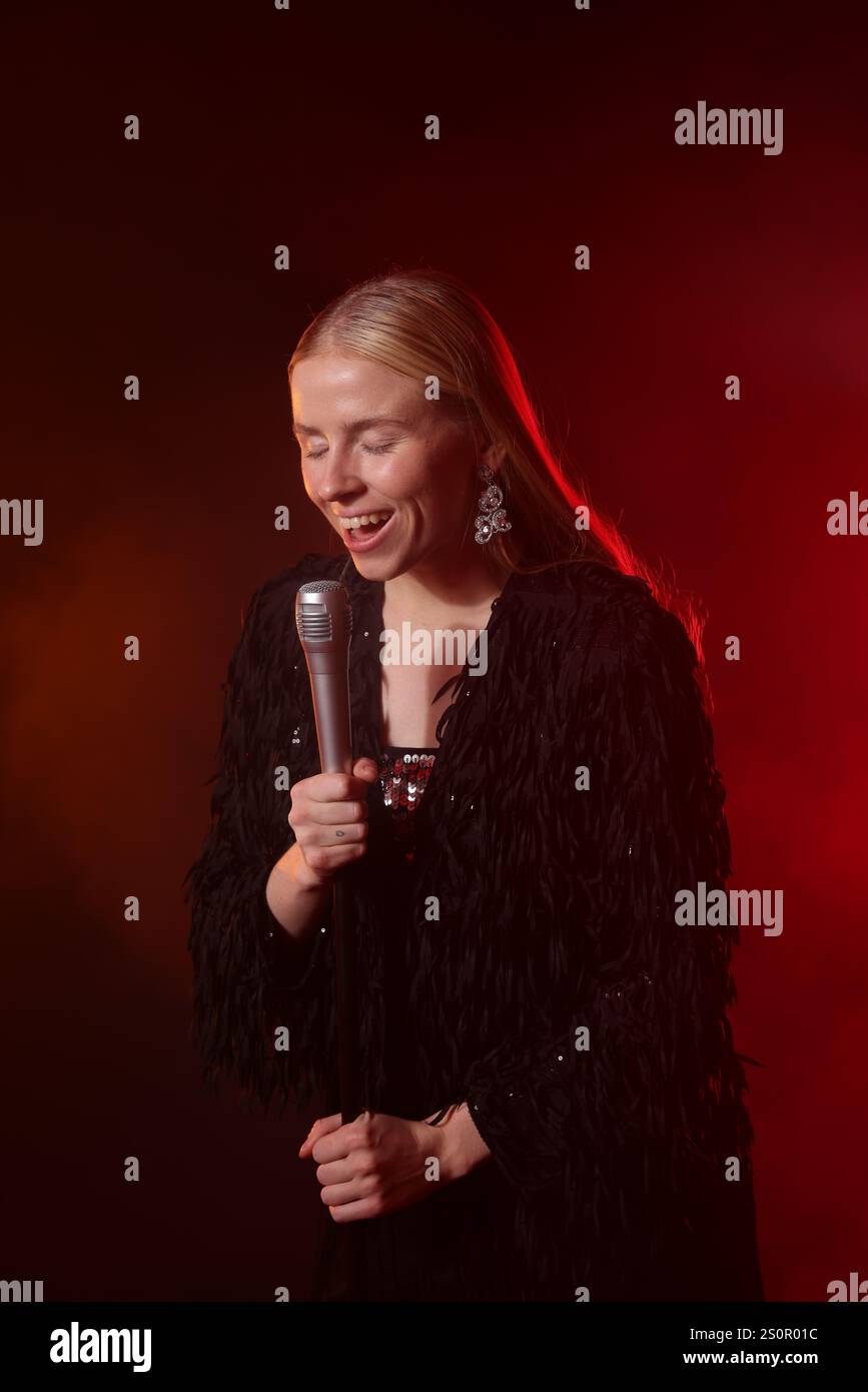 Beautiful singer performing on dark background with red light Stock ...