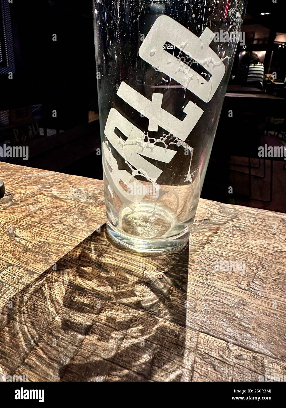 An empty glass on a wooden table in the gastro pub and brewery BRLO Brwhouse in Berlin Schoeneberg, Germany - Smartphone Captured Stock Image