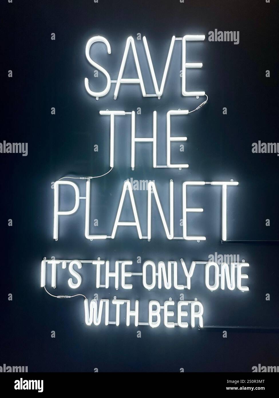 Neon sign in the BRLOW Brwhouse in Berlin saying Save the planet it's the only one with beer - Smartphone Captured Stock Image