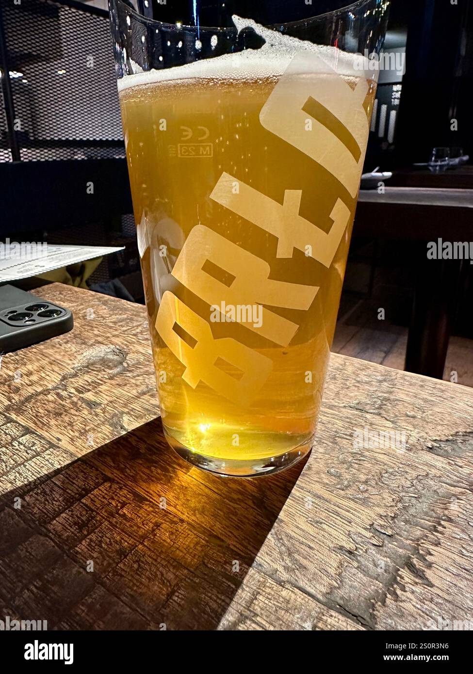 A glass of beer on a wooden table in the gastro pub and brewery BRLO Brwhouse in Berlin Schoeneberg, Germany, Concept: craft beer, drinking - Smartphone Captured Stock Image