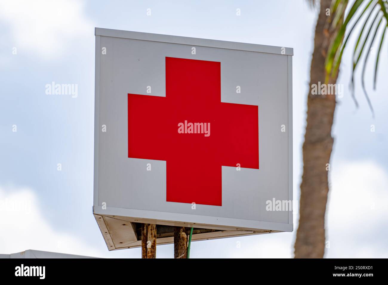 first aid medical cross on a box sign in front of blue sky. the cross is very important to the viewer Stock Photo