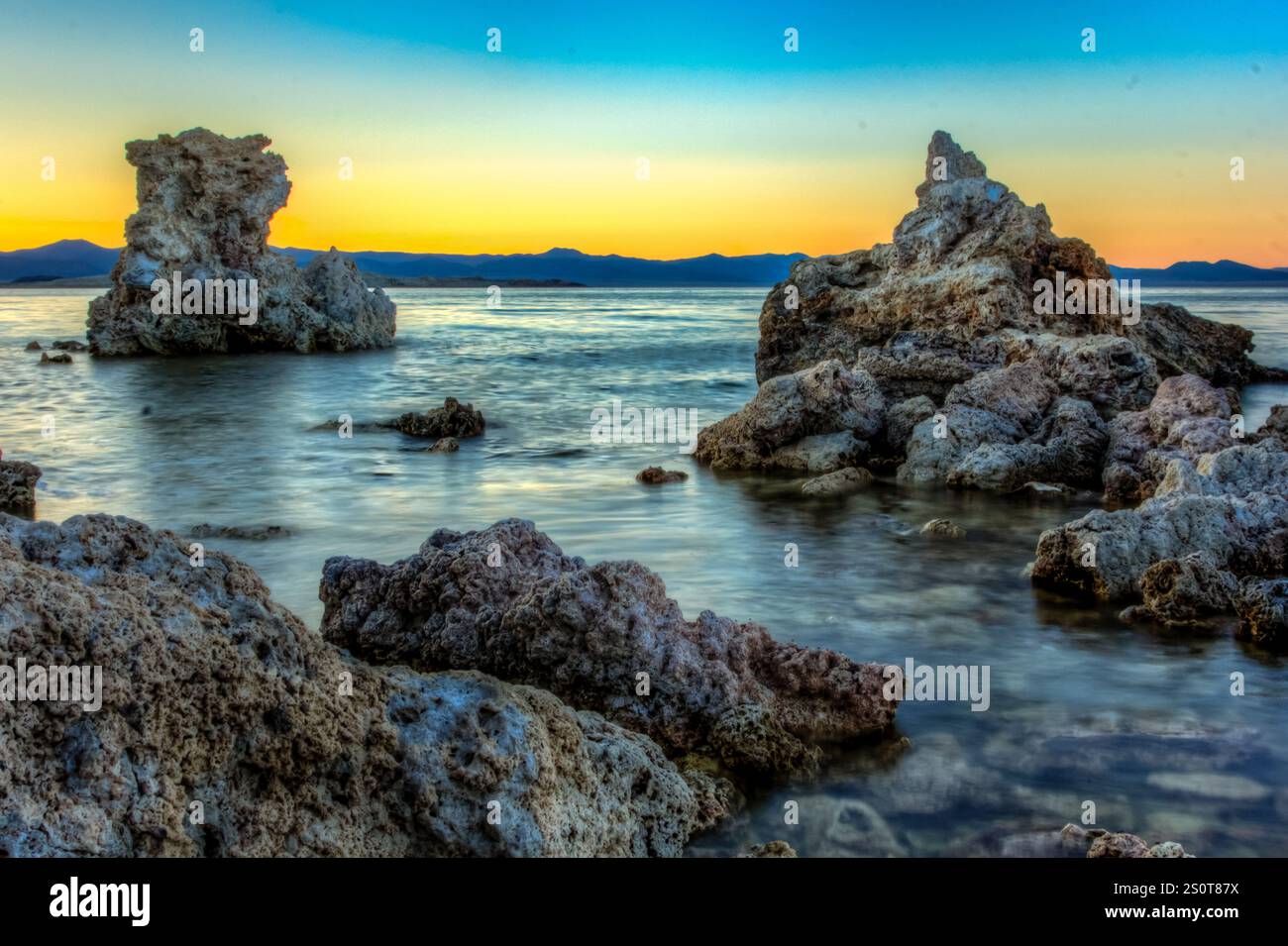 A rocky shoreline with a calm body of water in the background. The ...