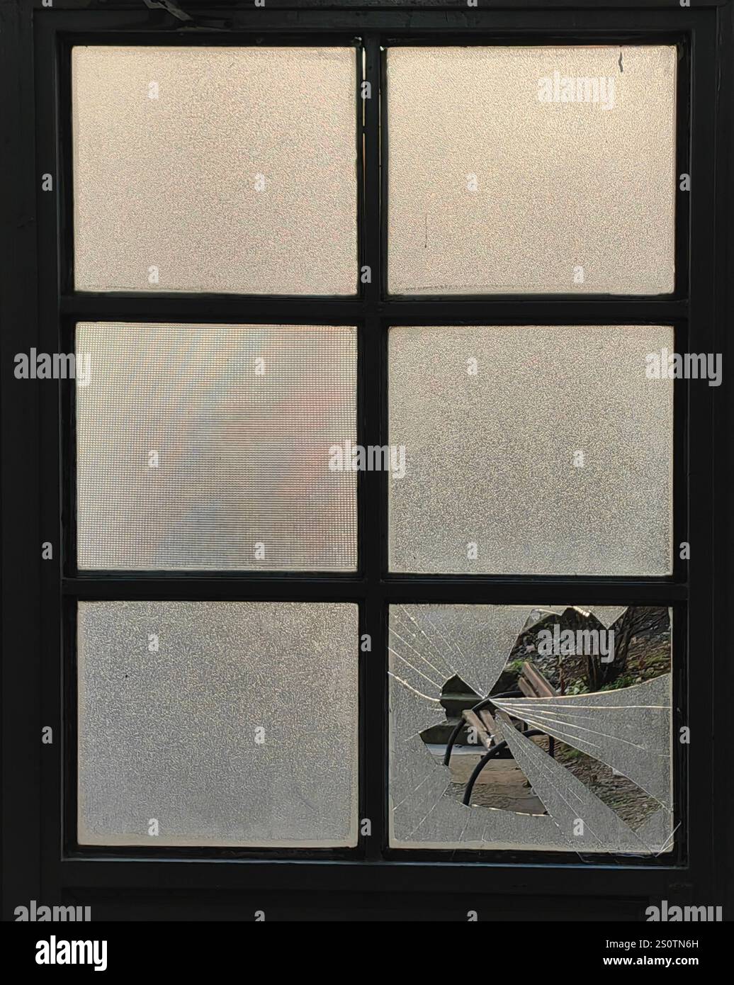 Shattered Perspective: Framed Park Bench Through Broken Glass Stock Photo