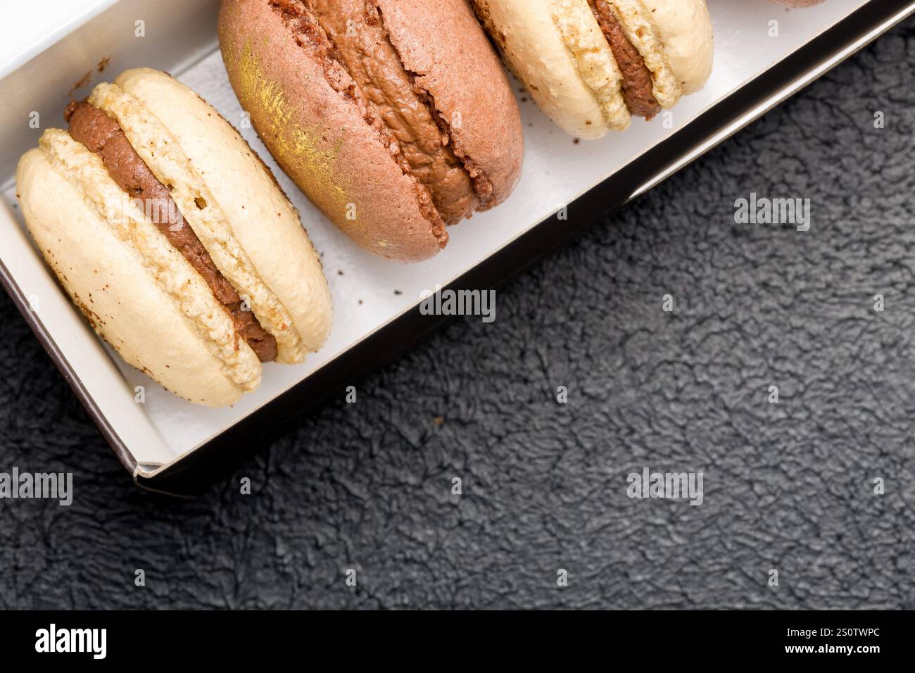 Macaroons in a black cardboard box on a dark background. Stock Photo