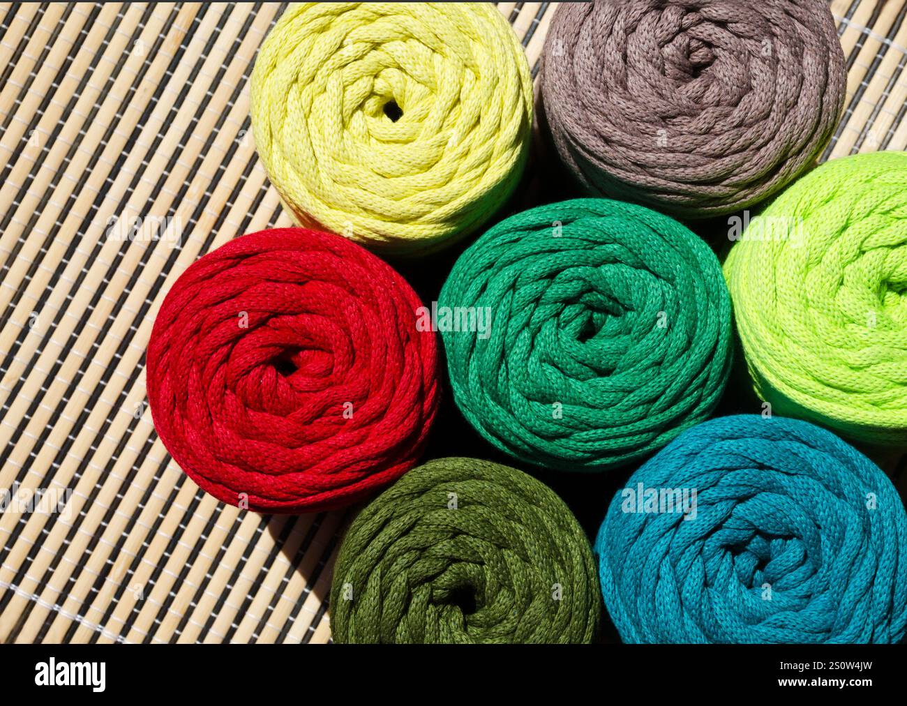 Colored skeins of thread for weaving macrame. Bright thread macro on a wooden background. Stock Photo