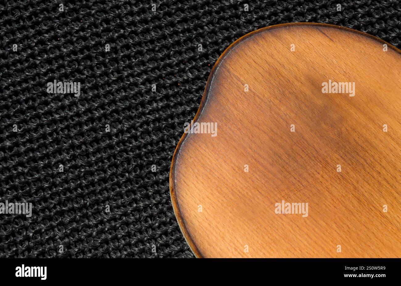 Cutting kitchen board on black raffia background. Great background for food. Stock Photo
