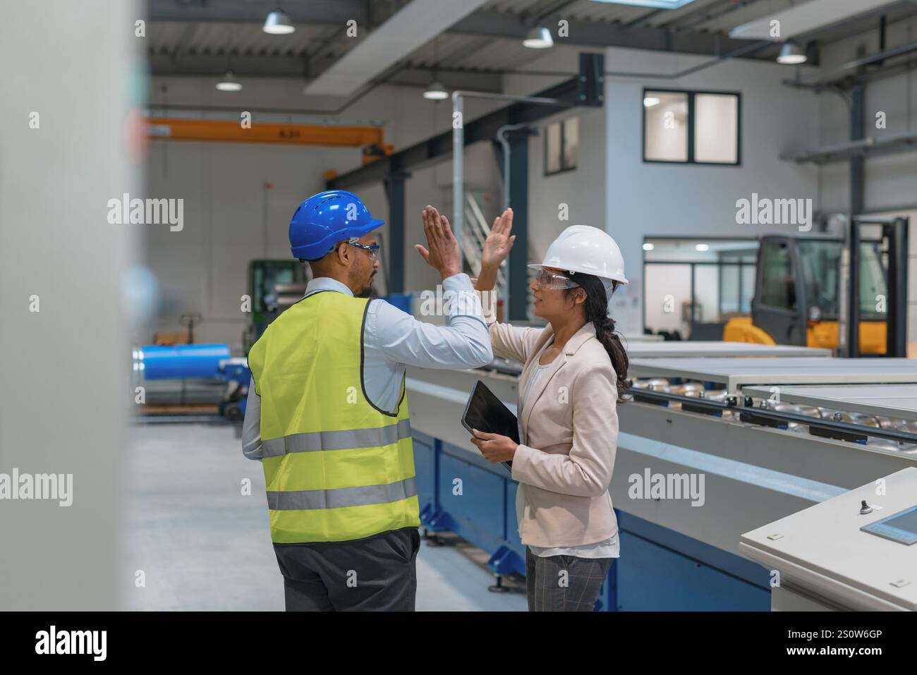 Female manager engineer giving high five to industry worker in manufacture factory. Stock Photo