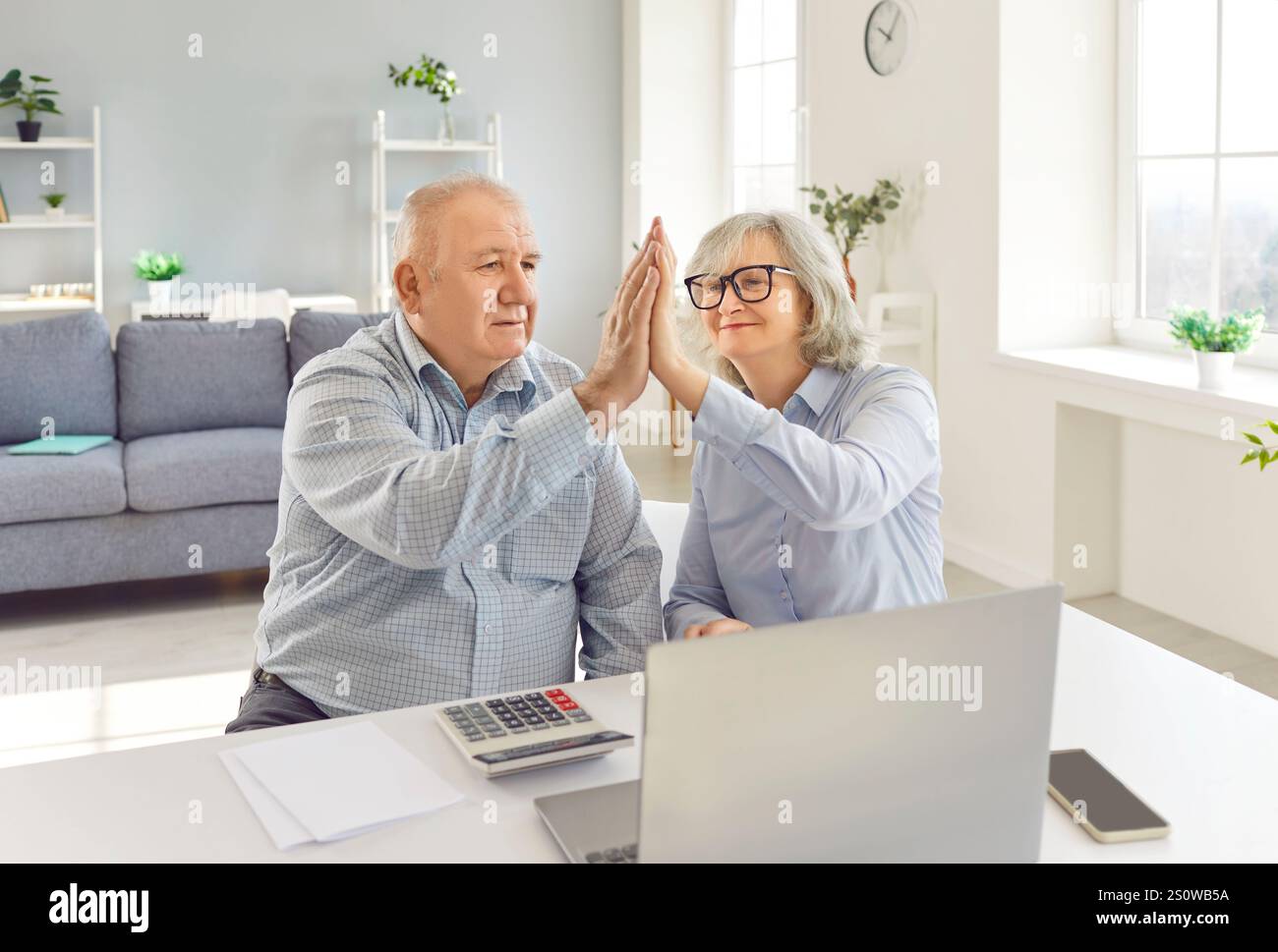 Senior happy couple calculating successful banking, payment online at laptop screen, feeling joy Stock Photo