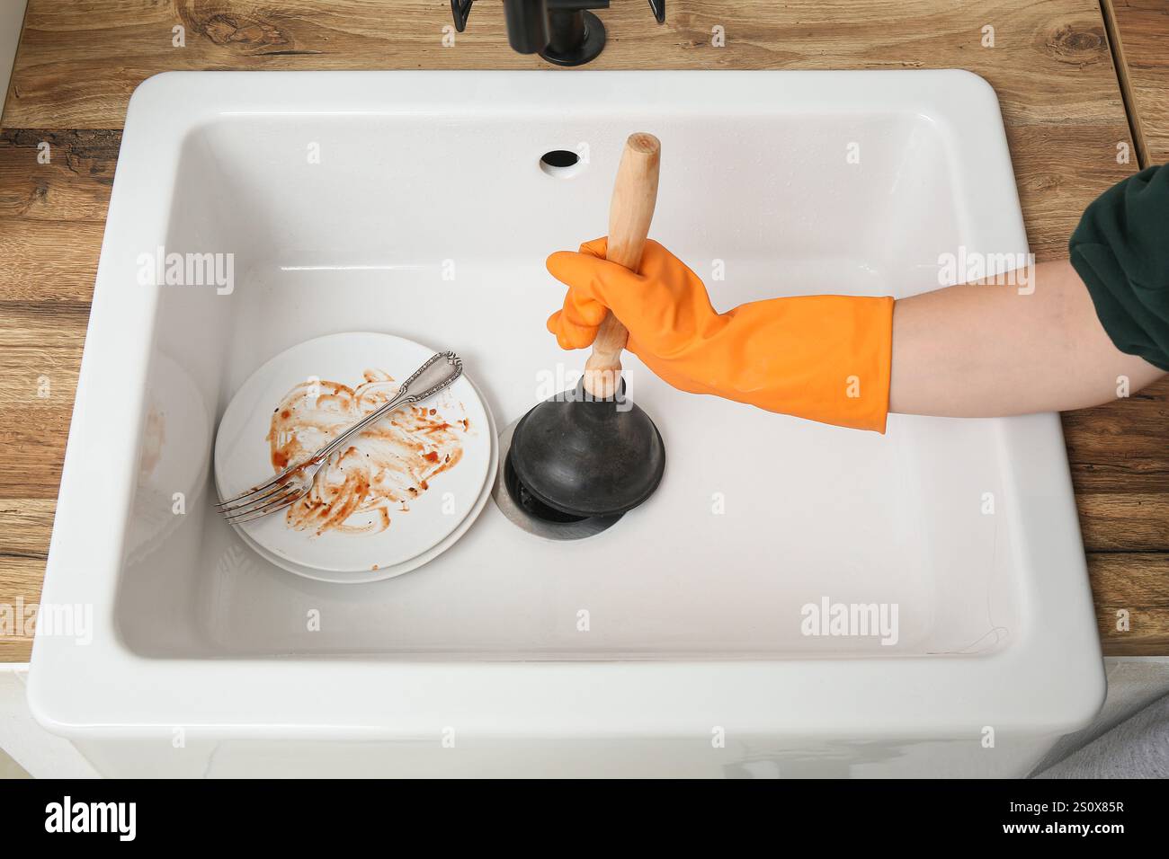 Woman cleaning clogged kitchen sink with plunger, closeup Stock Photo ...