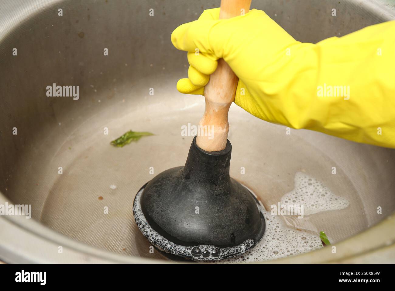 Woman cleaning clogged kitchen sink with plunger, closeup Stock Photo ...