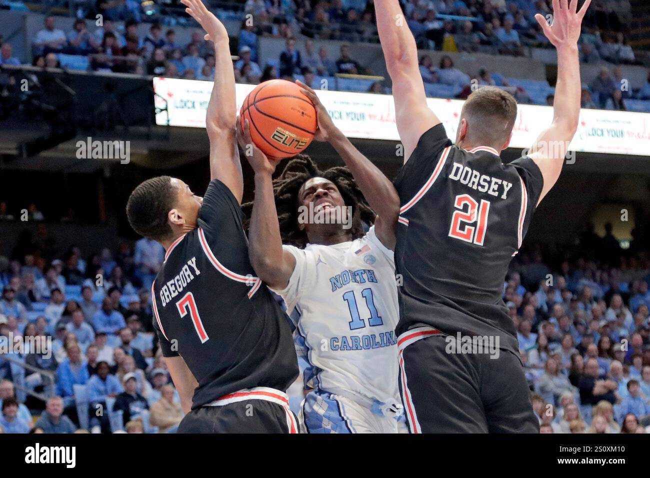 Ian Roche Guard North Carolina guard Ian Jackson (11) is defended by Campbell guards ...