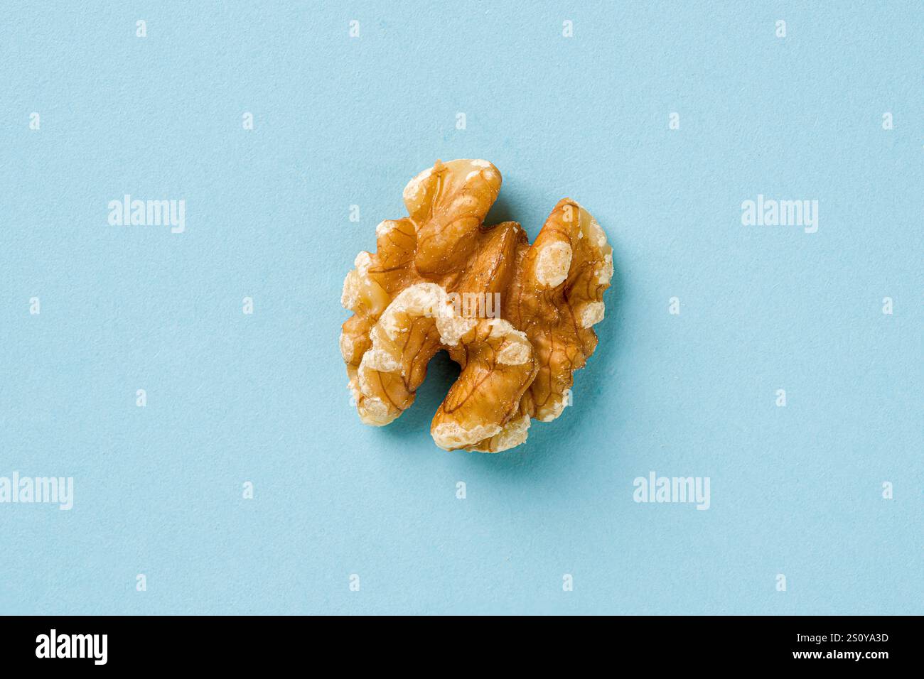 Top view of half walnut kernel on blue background Stock Photo