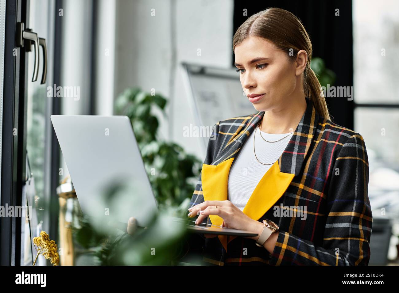 Attractive young woman focuses on her laptop in a chic office ...