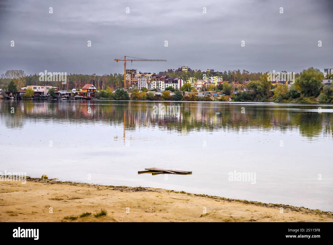 Scenic View of Damaged Residential Buildings in Irpin, Ukraine, by a Tranquil Lake Amid Autumn Trees Stock Photo